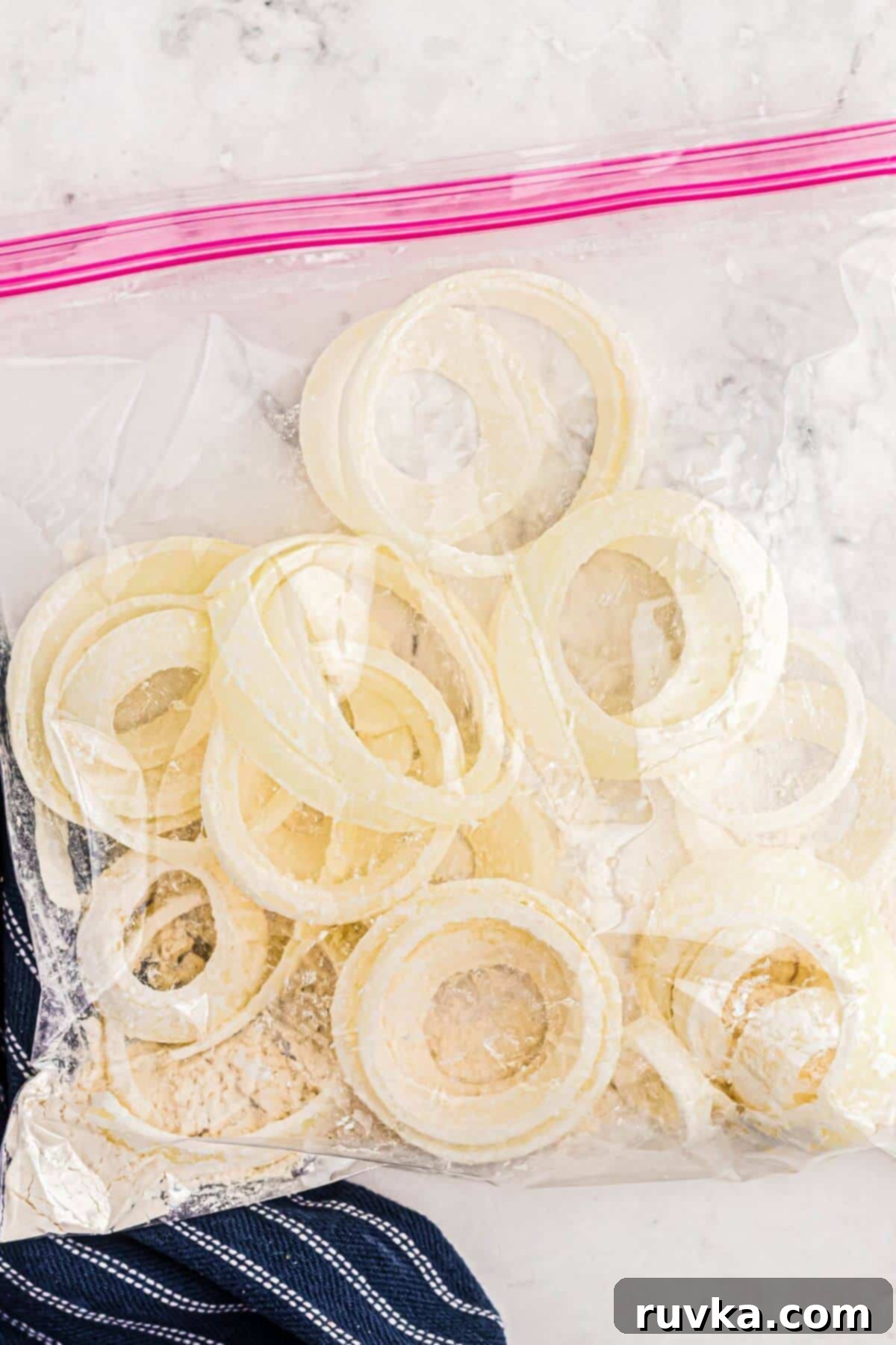 Guilt-Free Air-Fried Onion Rings 5 Onions sliced in a ziploc bag being mixed with flour.