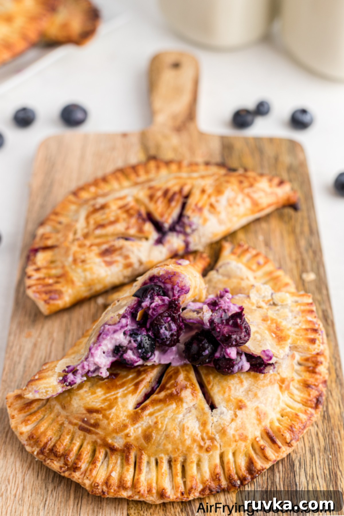 Crispy Air Fried Blueberry Pockets 2 Blueberry hand pies made in an air fryer, and placed on a cutting board.