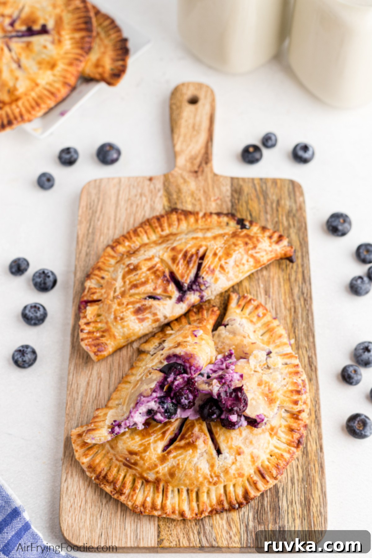 Crispy Air Fried Blueberry Pockets 12 Air fried hand pies stuffed with blueberries and cream cheese, served on a cutting board.