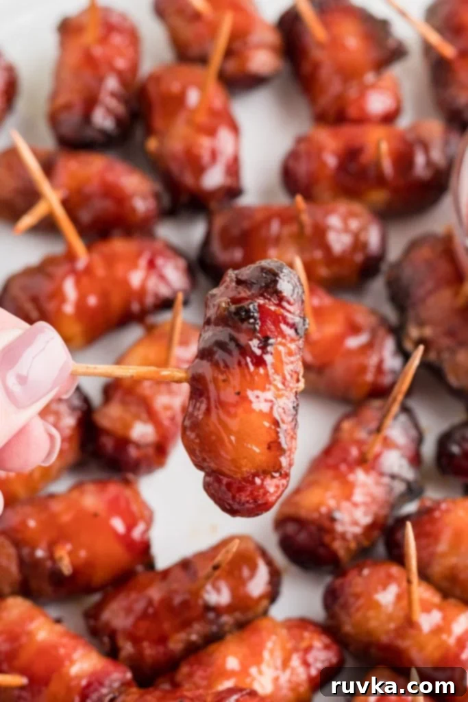 Crispy Air-Fried Bacon-Wrapped Smokies 9 BBQ coated bacon wrapped smokies being held by the toothpick.