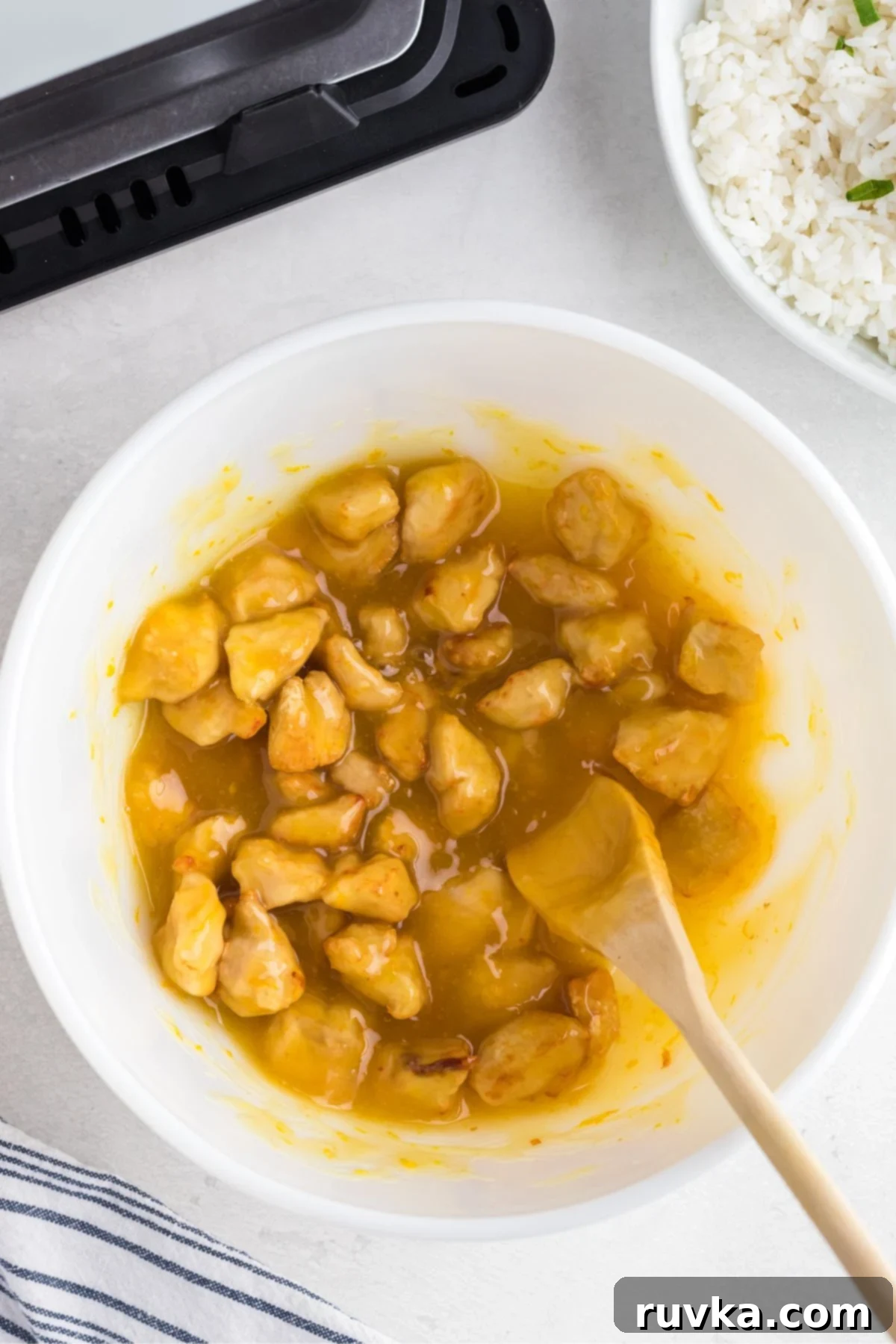 Golden Crispy Air Fryer Orange Chicken 7 chicken being tossed with orange sauce