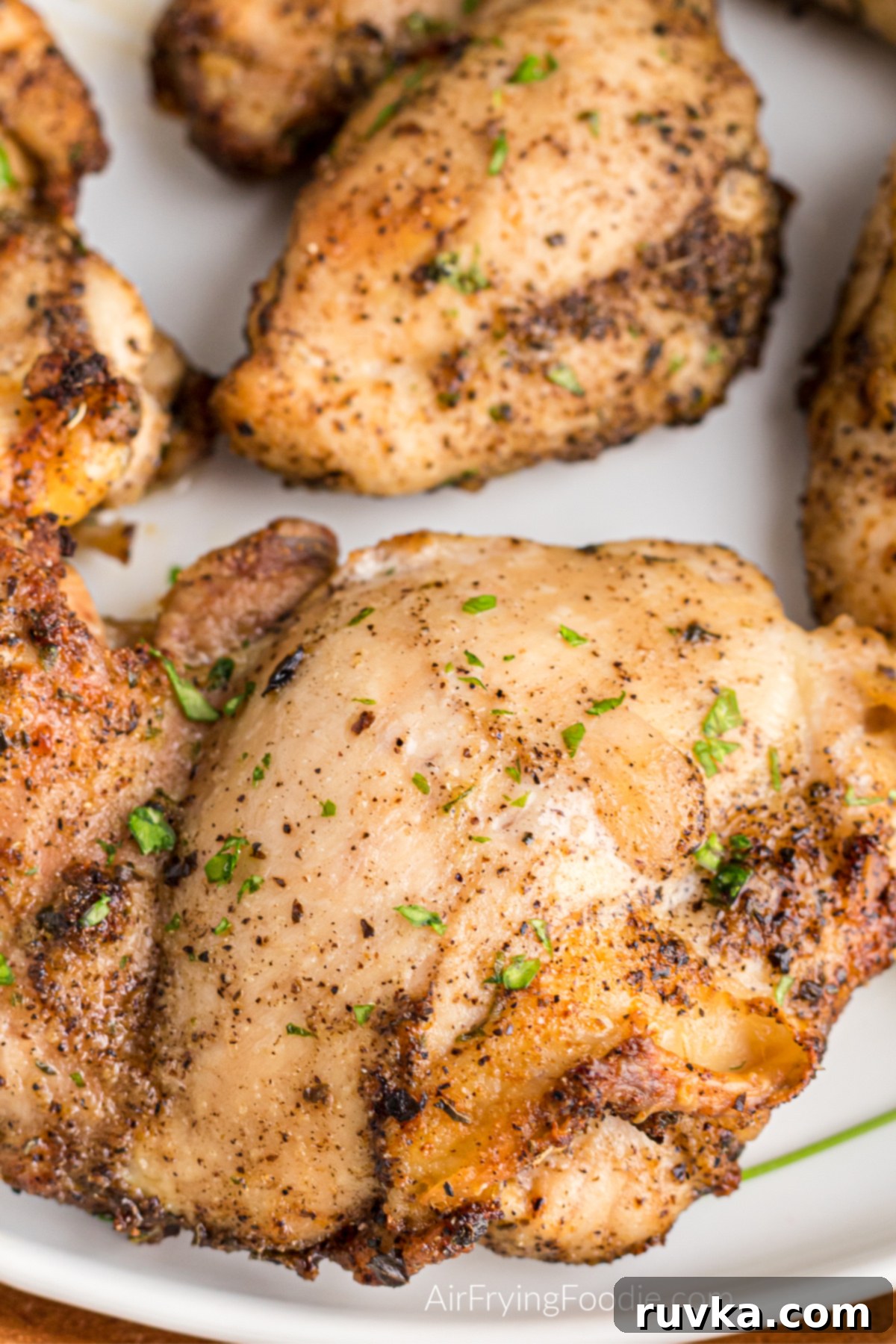 Crispy Air-Fried Chicken Thighs 8 Seasoned boneless chicken thighs made in the air fryer and served on a white plate.