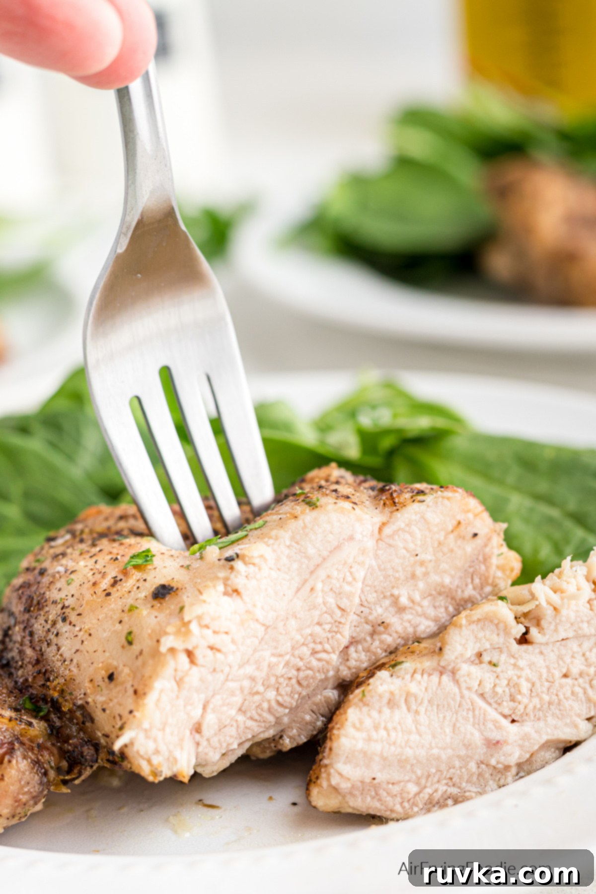 Crispy Air-Fried Chicken Thighs 9 Sliced chicken thighs with a fork on a plate with salad.