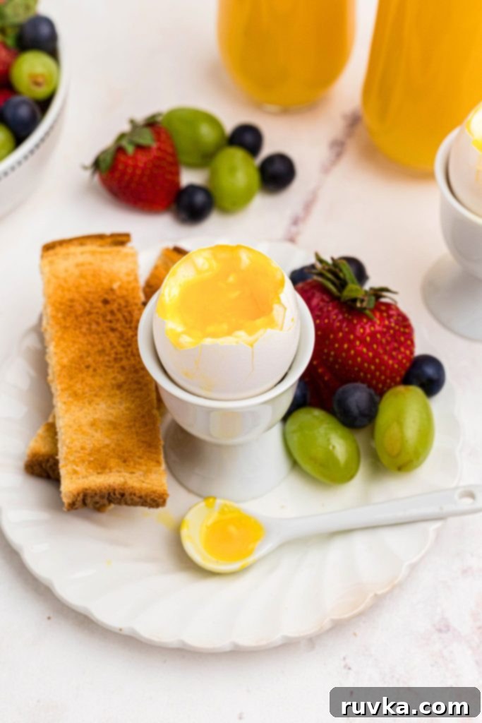 Air Fryer Jammy Eggs 2 Lightly cooked soft boiled egg with toast and fruit on a white plate.