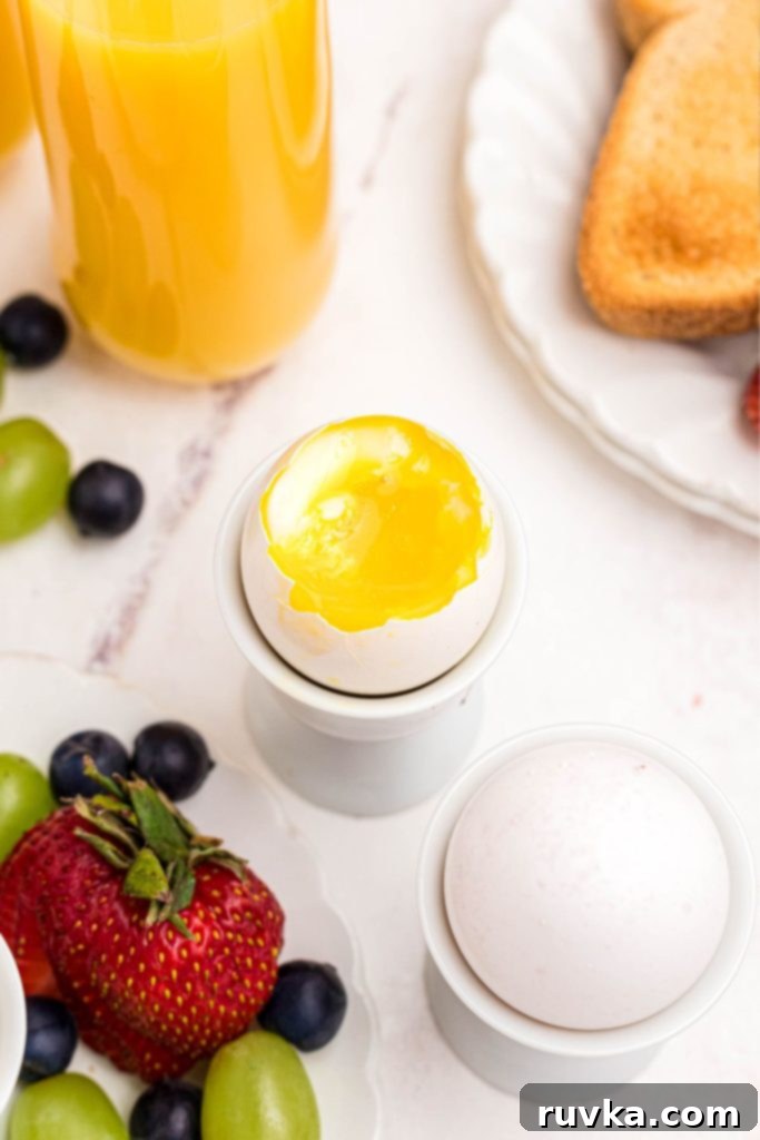 Air Fryer Jammy Eggs 6 Slightly runny yolk inside of a cooked but cracked egg in front of fresh fruit.