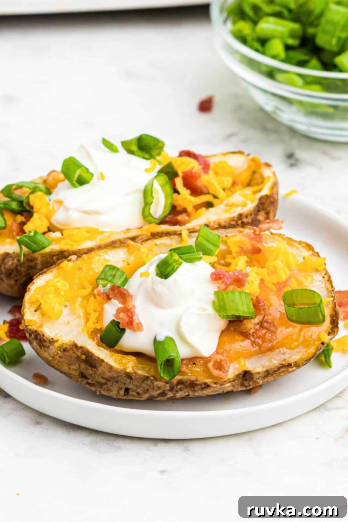 Crispy Air Fryer Potato Skins 2 Golden brown baked potato on a small white plate.