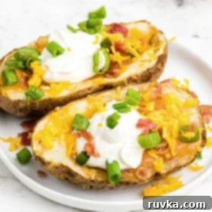 Crispy Air Fryer Potato Skins 8 Potato skins topped with sour cream, cheese, bacon, and green onion, served on a white plate