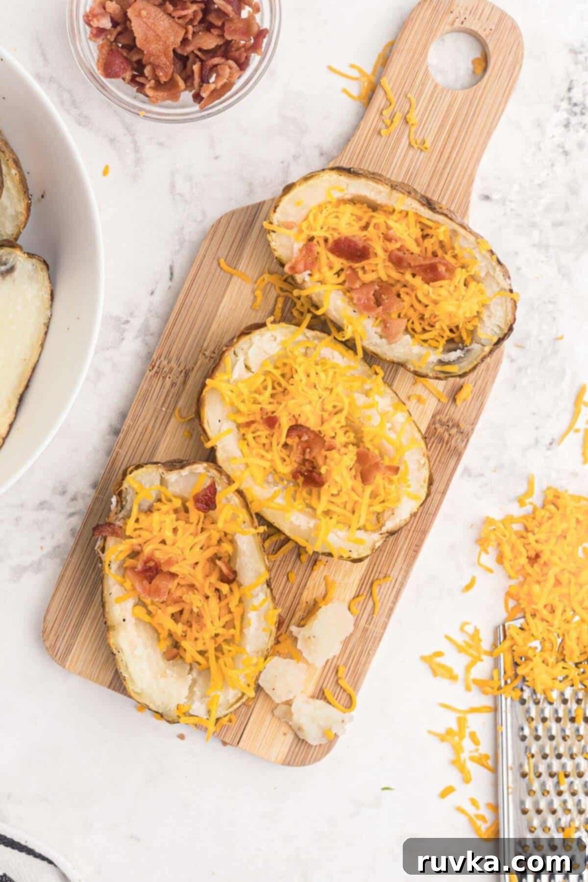 Crispy Air Fryer Potato Skins 4 Baked potatoes scooped out then filled with shredded cheese and bacon crumbles.