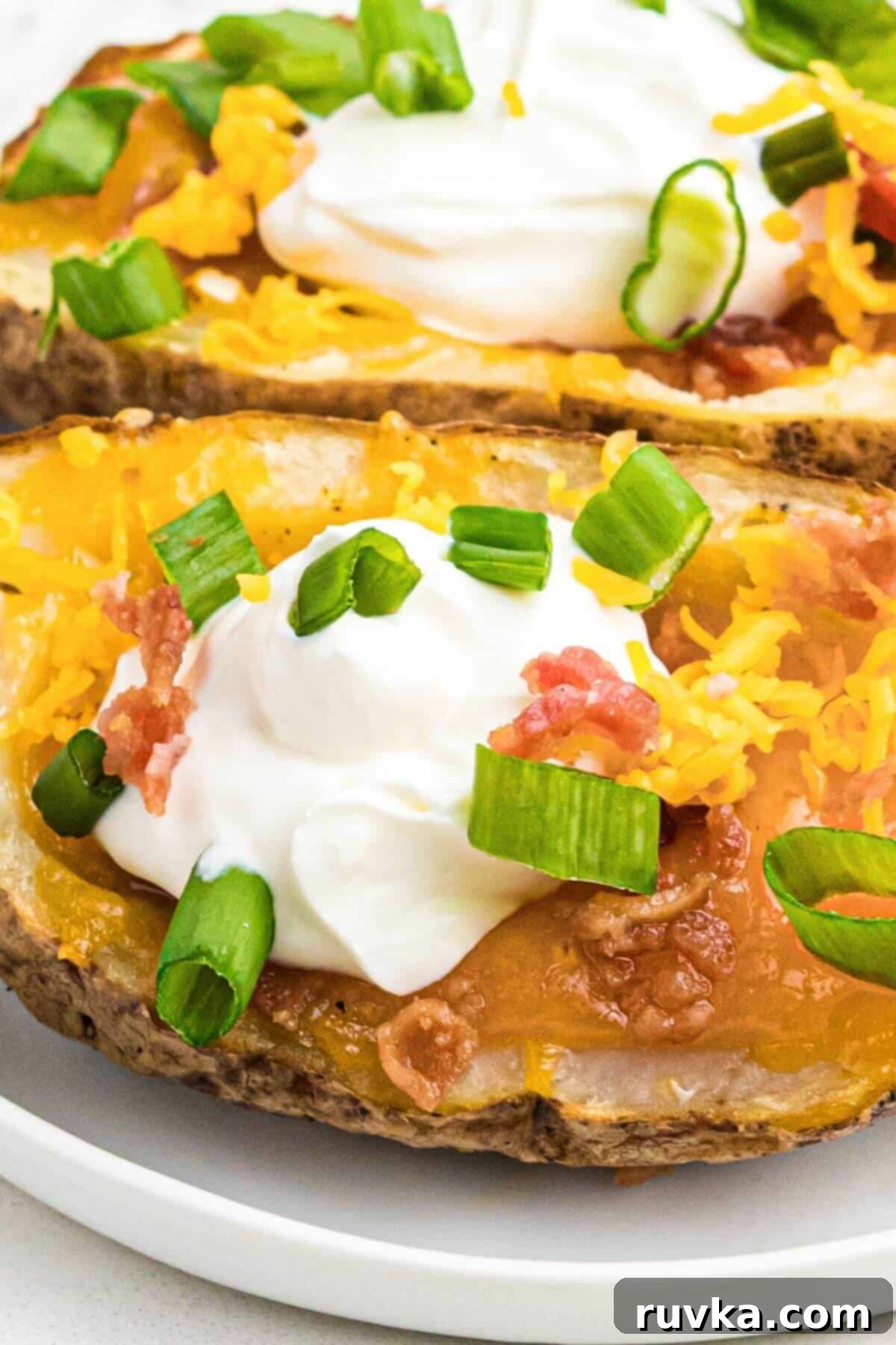 Crispy Air Fryer Potato Skins 7 Close up photo of potato skin topped with cheese, bacon, sour cream and green onion.