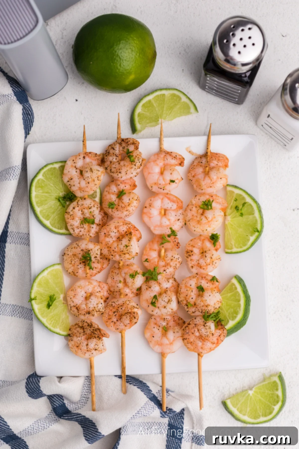 Easy Air Fryer Shrimp Skewers 2 Shrimp skewers made in the air fryer and served with slices of lime.