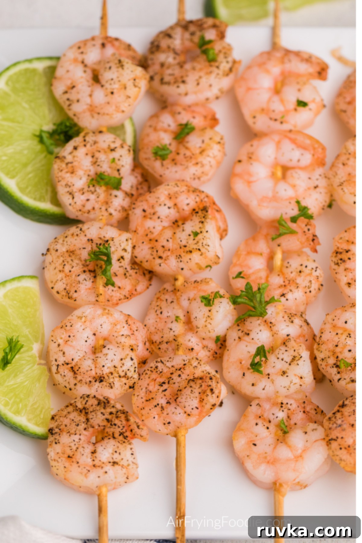 Easy Air Fryer Shrimp Skewers 7 Shrimp skewers made in the air fryer and served on a white plate.