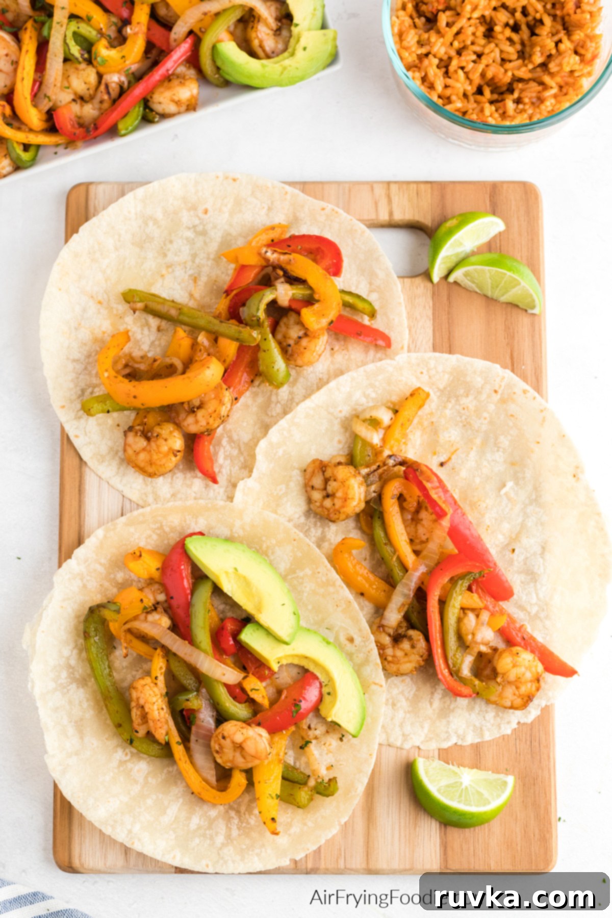 Effortless Air Fryer Shrimp Fajitas 9 Air fryer shrimp fajitas served on tortillas with sliced avocado and a slice of lime.