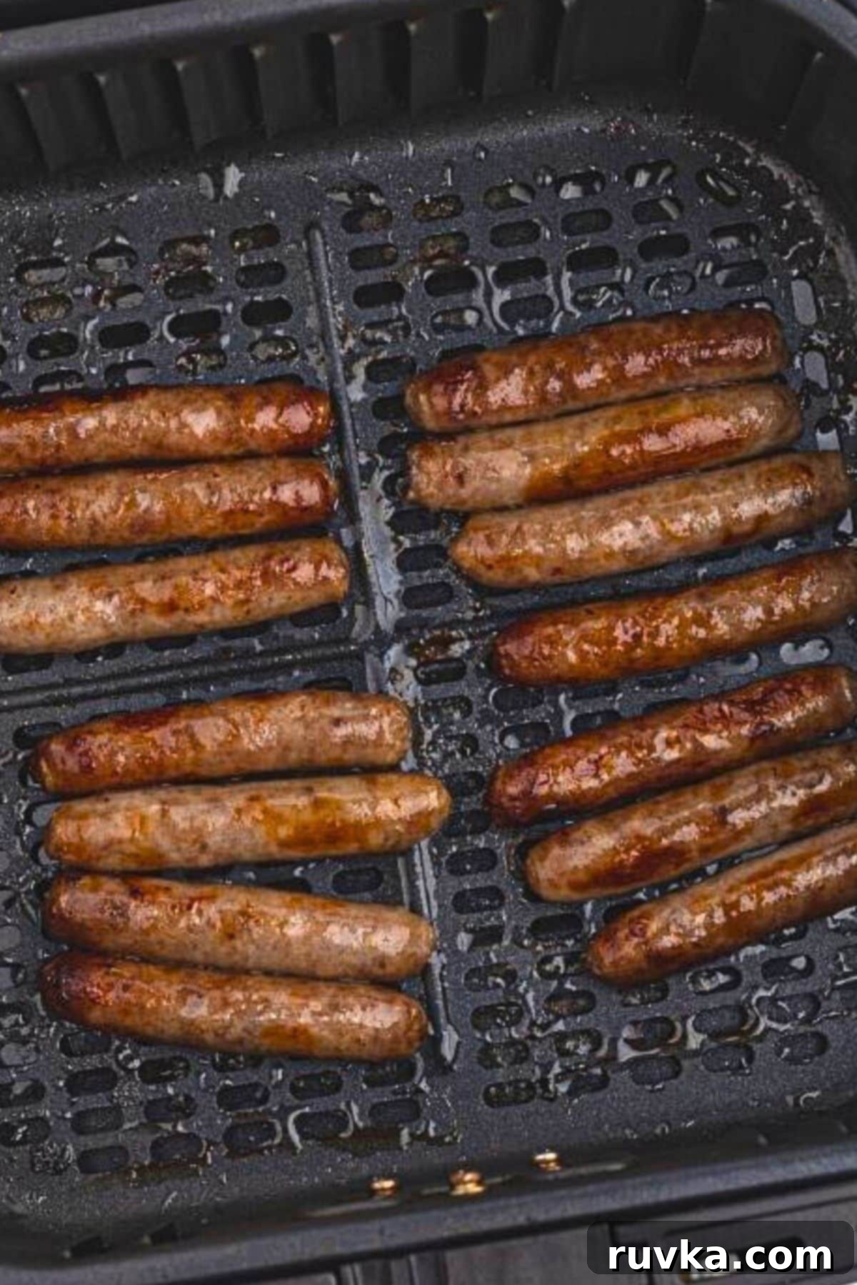 Crispy Air Fryer Sausage Links 5 Golden brown, cooked sausage links in the air fryer basket after being cooked.