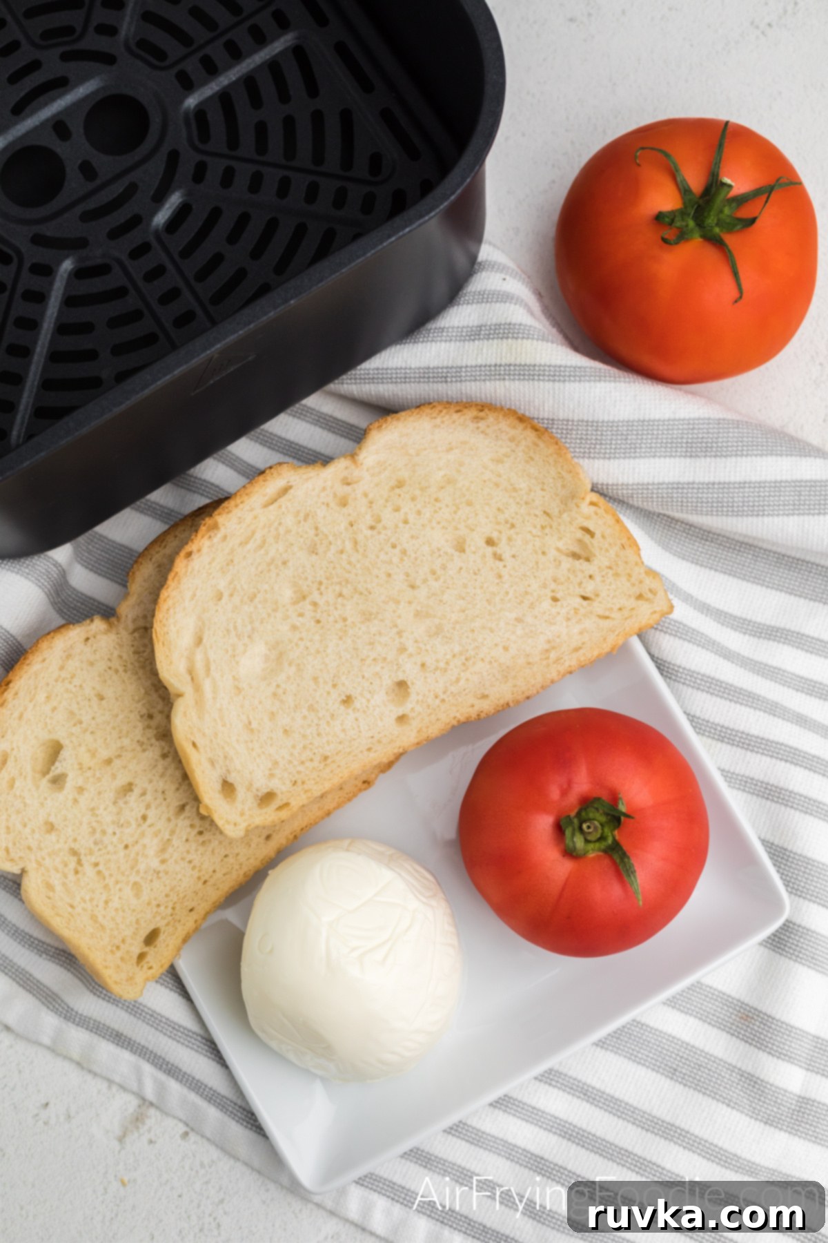 Air Fryer Caprese Melts 3 Mozzarella cheese, tomato, and bread on a white plate.