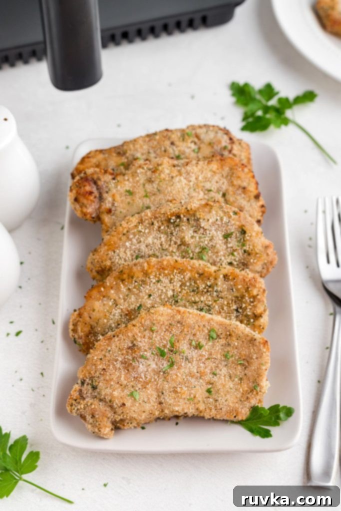 Golden Crispy Air Fryer Pork Chops 2 Golden brown breaded pork chops on a white plate, ready to be served
