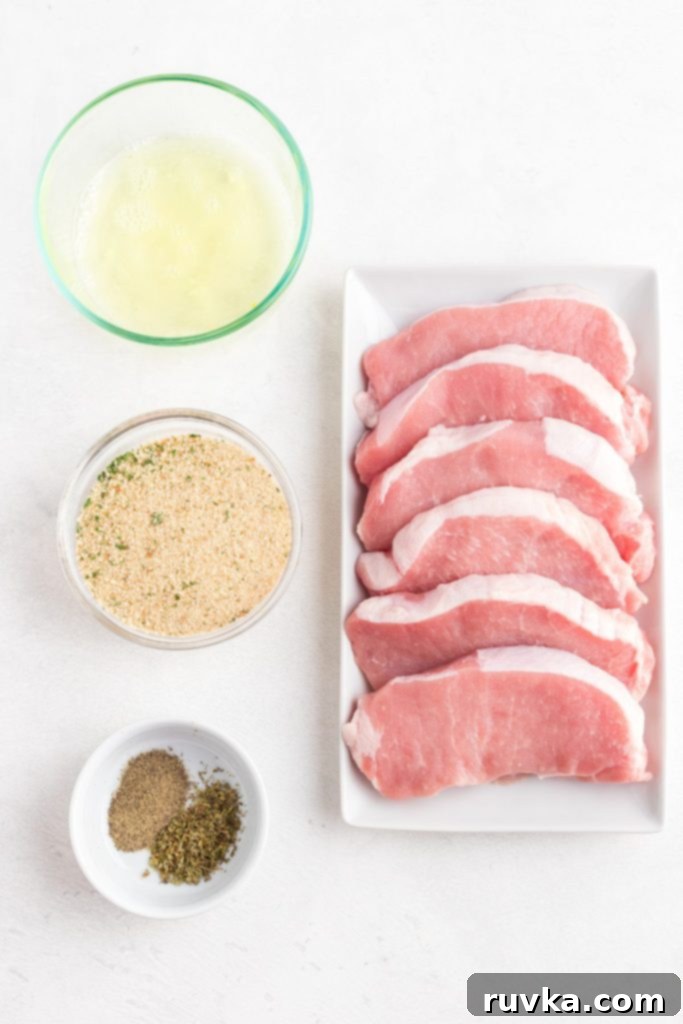 Golden Crispy Air Fryer Pork Chops 3 Ingredients needed to make breaded pork chops laid out on a white marble table.