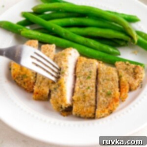 Golden Crispy Air Fryer Pork Chops 10 Golden breaded pork chop on a white plate with green beans as a side.