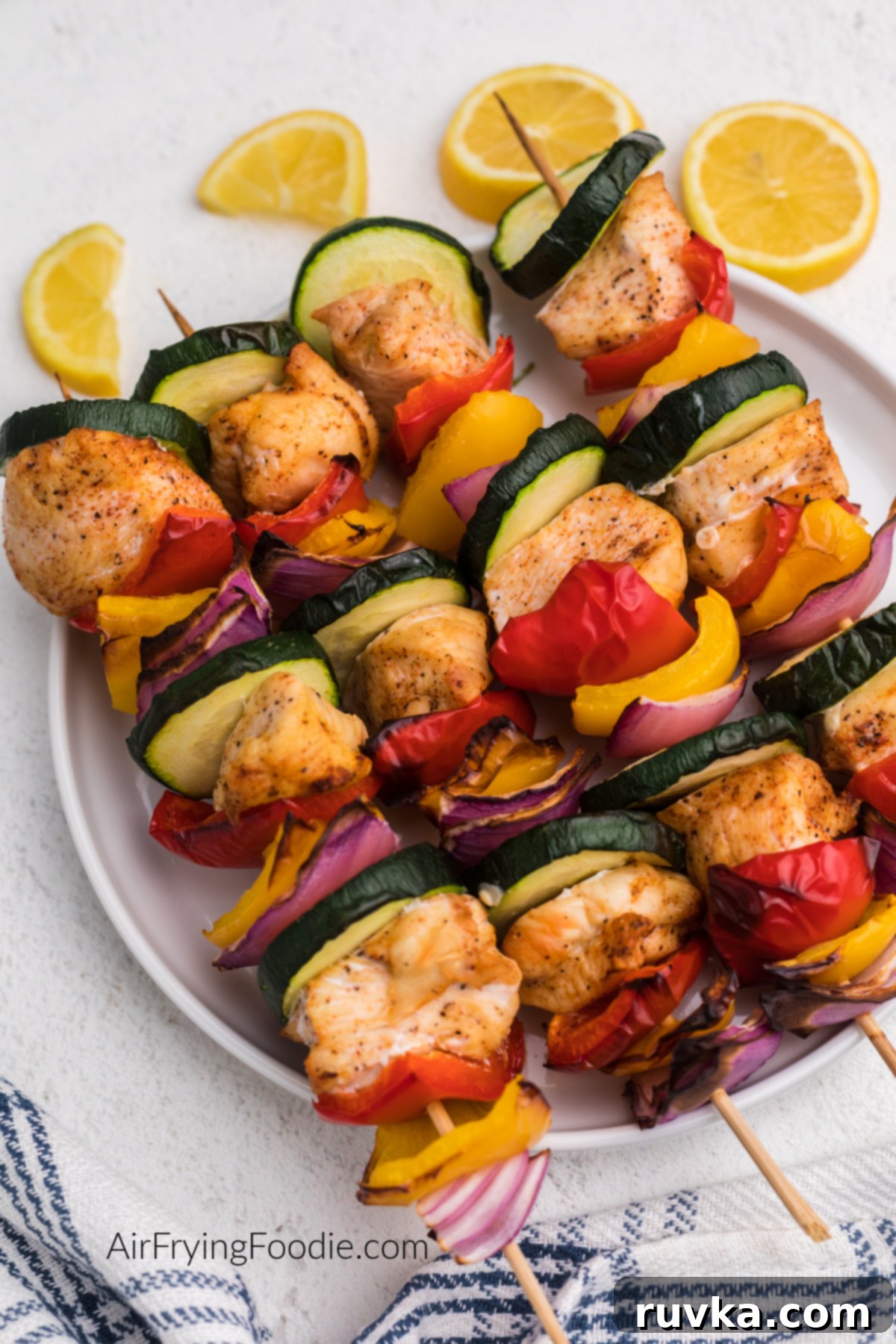 Easy Air Fryer Chicken Kabobs 2 Chicken kabobs made in the air fryer and served on a white plate.