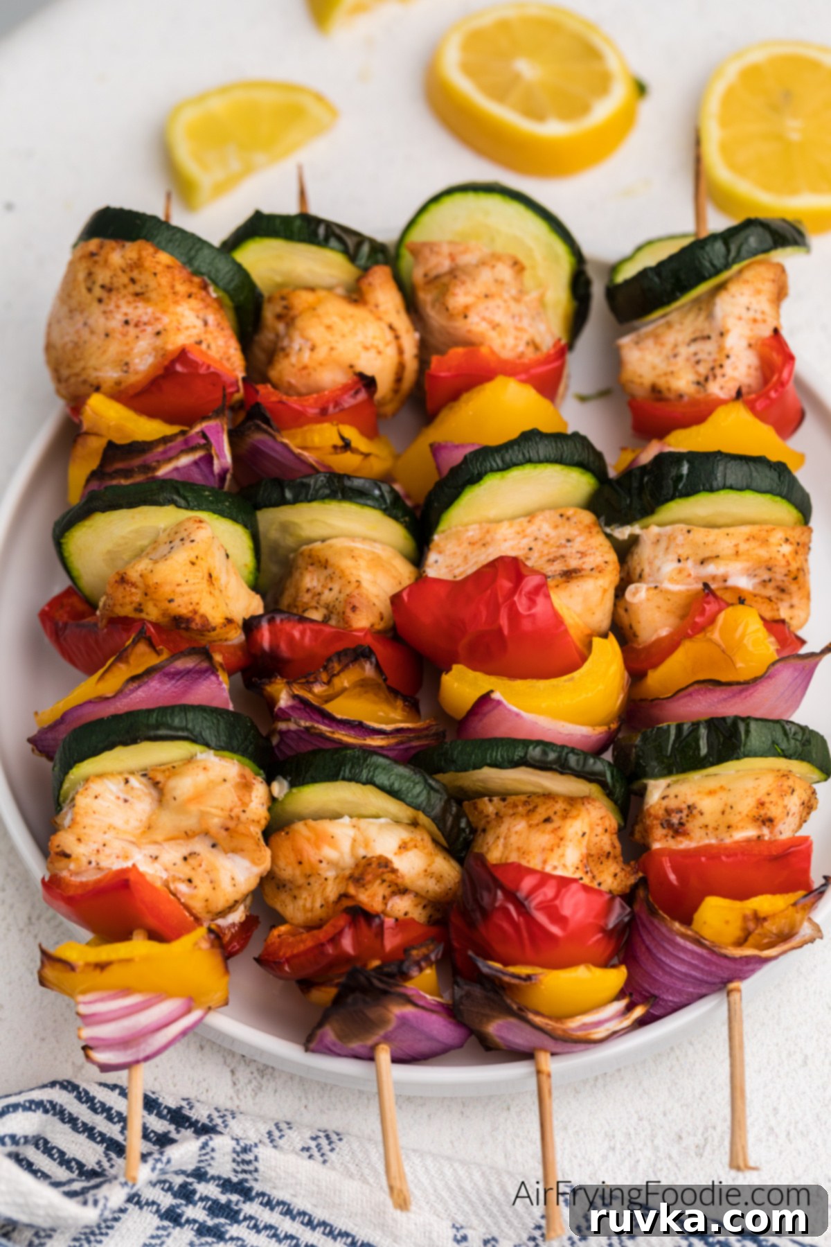 Easy Air Fryer Chicken Kabobs 8 Chicken kabobs made with chicken breast and vegetables and served on a white plate.