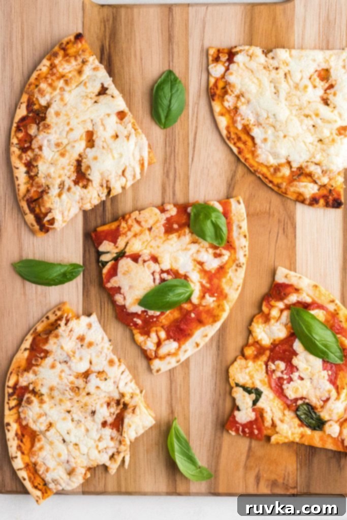 Crispy Air Fryer Tortilla Pizzas 2 Tortillas covered with melted cheese and pizza toppings on a wooden cutting board.