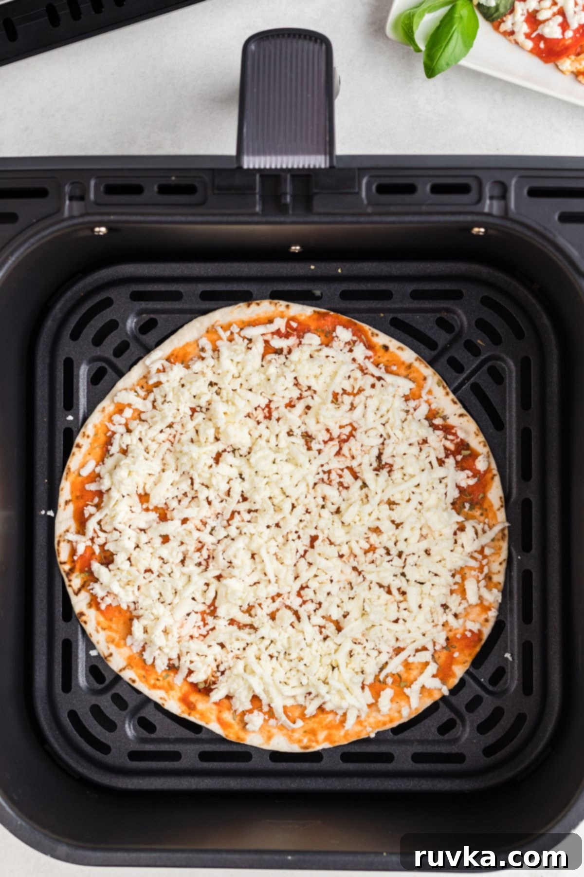 Crispy Air Fryer Tortilla Pizzas 5 Tortilla topped with pizza sauce and mozzarella cheese in the air fryer basket.