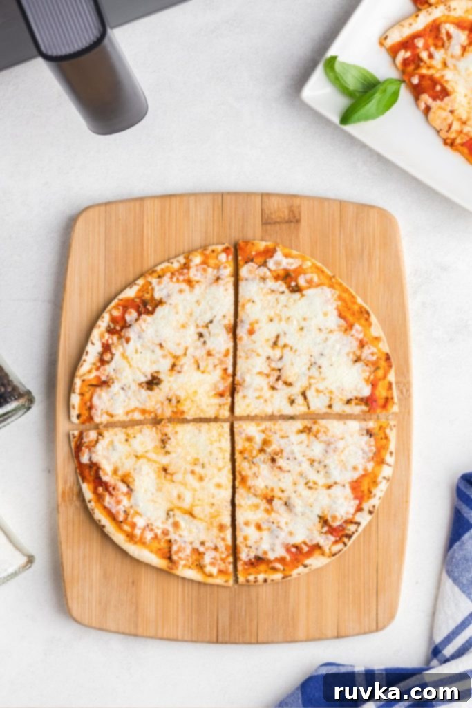 Crispy Air Fryer Tortilla Pizzas 7 Tortilla pizza with melted cheese on a wooden cutting board