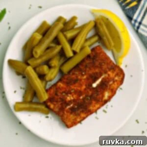 Air Fryer Favorites for Memorial Day 13 Overhead photo of air fried Mahi Mahi on a white plate with green beans and a lemon slice.