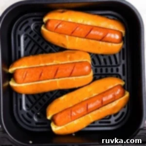 Air Fryer Favorites for Memorial Day 6 Juicy brown hot dogs in buns in the air fryer basket.