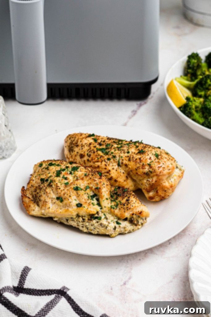 Crispy Air Fryer Stuffed Chicken 8 Golden seasoned stuffed chicken breasts on a white plate in front of an air fryer.