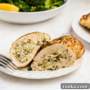 Crispy Air Fryer Stuffed Chicken 10 Golden stuffed chicken on a white plate with a bowl of broccoli behind the plate.
