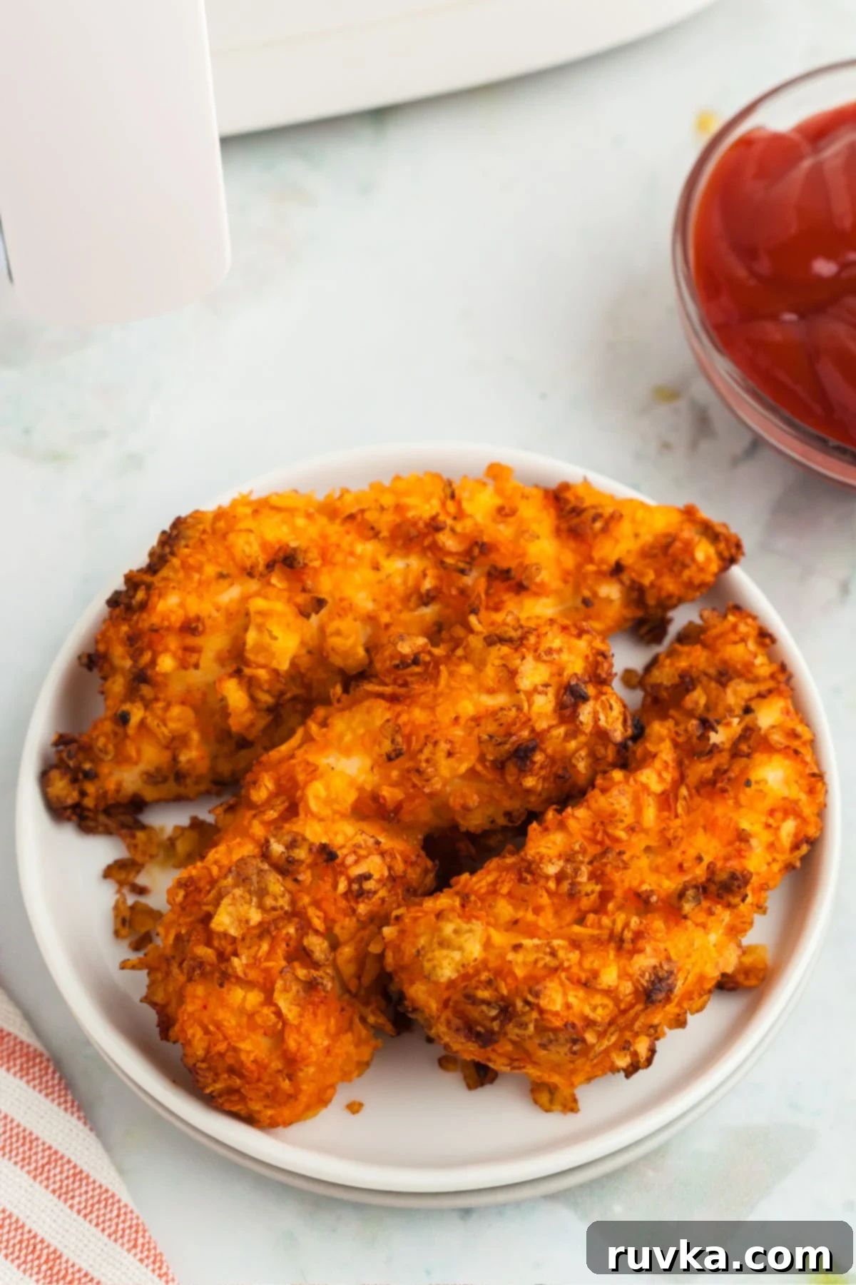 Delicious Air Fryer Chicken Recipes Made Easy 15 Crispy air fried Dorito chicken, covered in crushed chips, served on a white plate ready to be devoured.