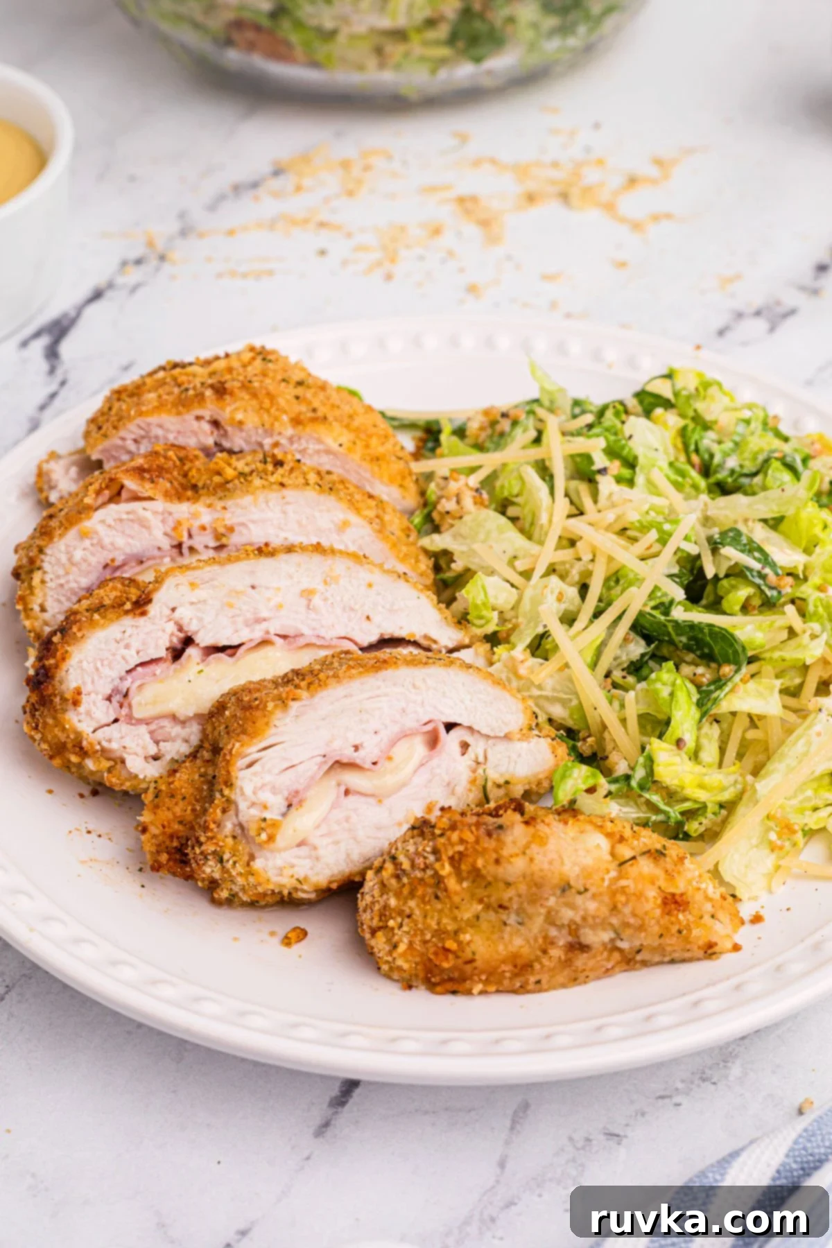 Delicious Air Fryer Chicken Recipes Made Easy 16 Air fried Chicken Cordon Bleu, sliced to reveal savory ham and creamy cheese, served on a white plate.
