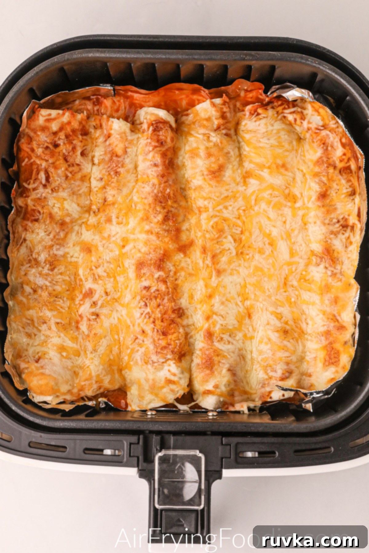 Delicious Air Fryer Chicken Recipes Made Easy 28 Air fried chicken enchiladas, cheesy and bubbling, in the basket of the air fryer.