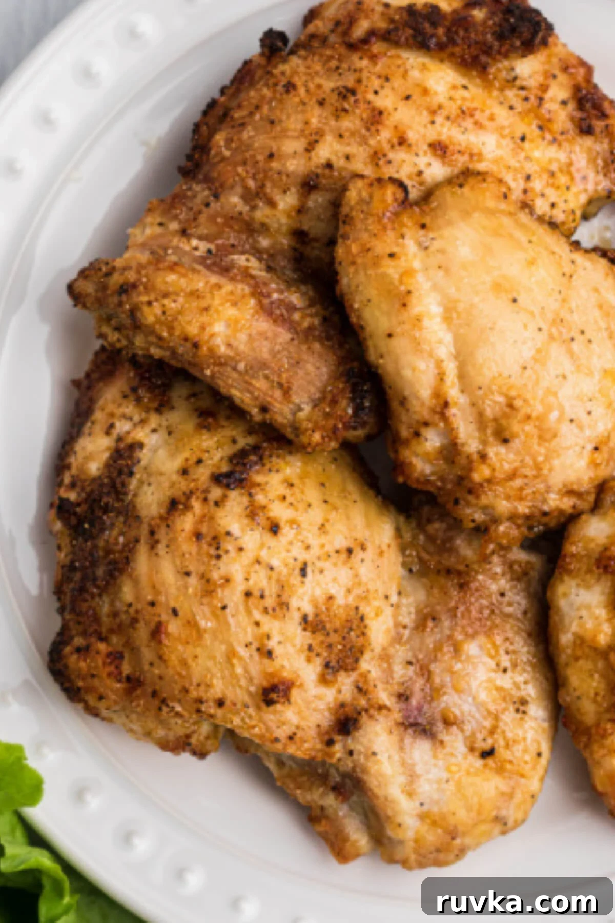 Delicious Air Fryer Chicken Recipes Made Easy 29 Air fried chicken thighs, beautifully seasoned and cooked, served on a white plate with a garnish of fresh herbs.