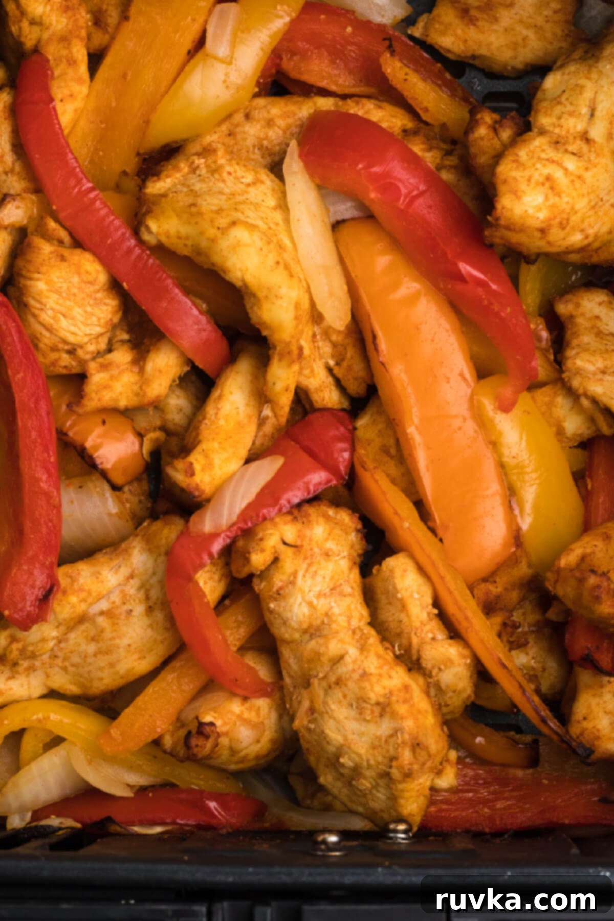 Delicious Air Fryer Chicken Recipes Made Easy 36 Colorful air fryer chicken fajitas with bell peppers and onions, served on a white plate with a side of tortillas.