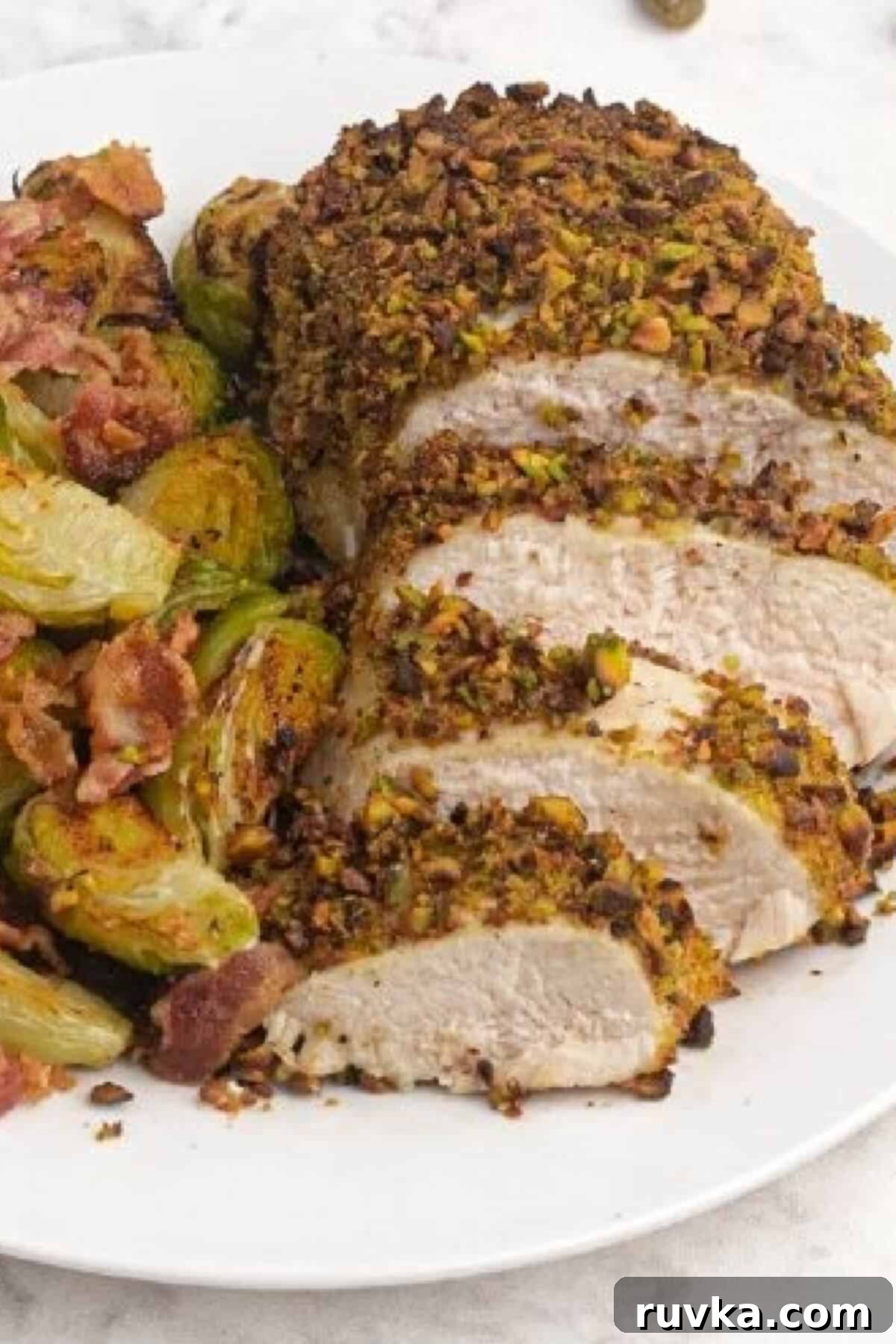 Delicious Air Fryer Chicken Recipes Made Easy 38 Air fryer pistachio crusted chicken, garnished with fresh herbs, served on a white plate with roasted brussel sprouts and crispy bacon.