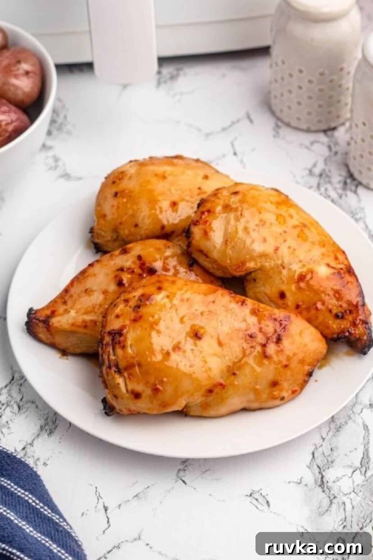 Delicious Air Fryer Chicken Recipes Made Easy 45 Air fryer peach glazed chicken, juicy and sweet, served on a white plate with a sprig of fresh herbs.