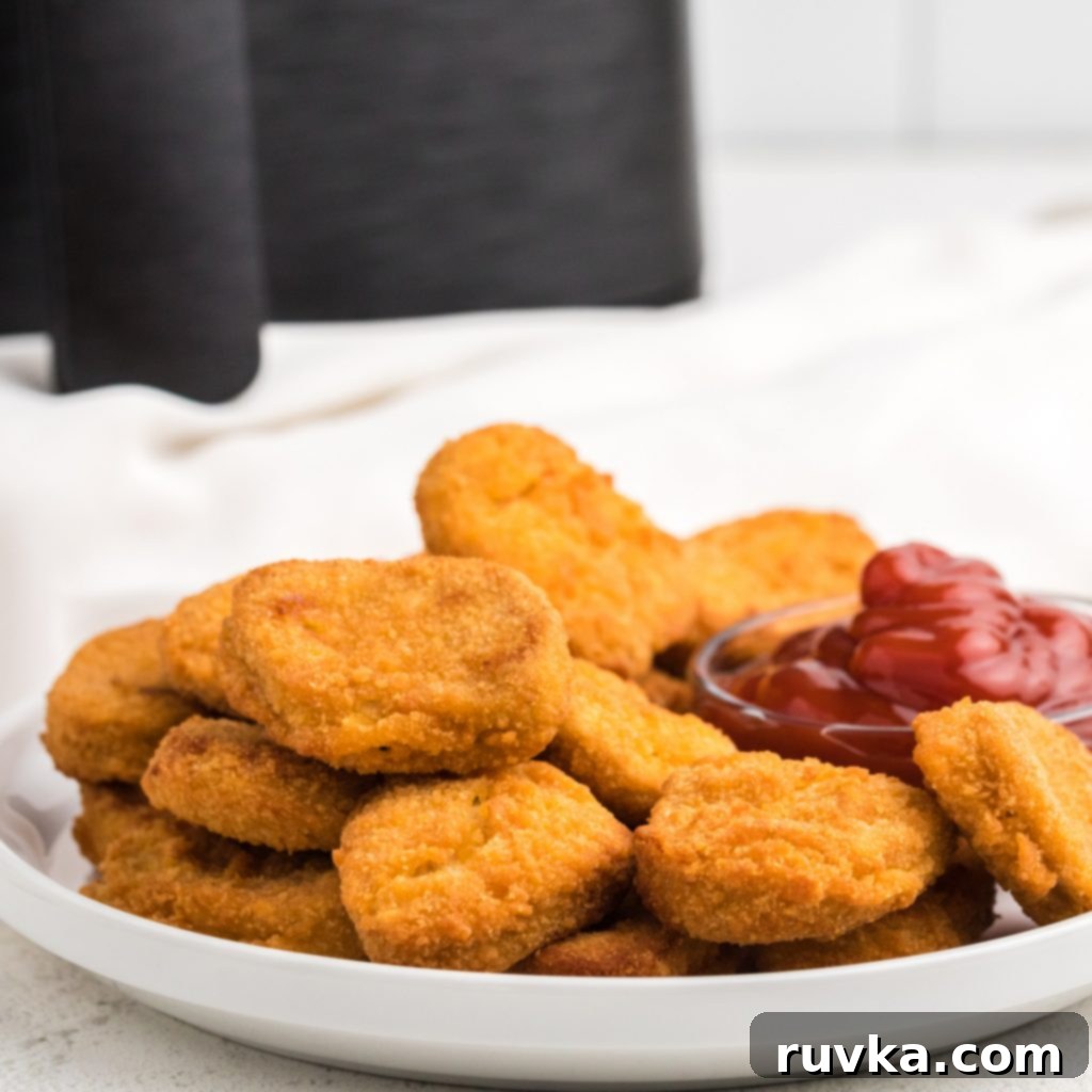 Delicious Air Fryer Chicken Recipes Made Easy 7 Perfectly air fried frozen chicken nuggets on a white plate with a side of ketchup dipping sauce.