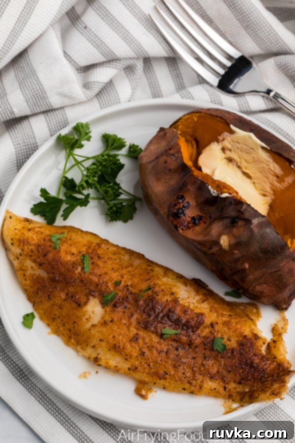 Air Fryer Swai Fish 3 Blackened swai fish made in the Air Fryer on a white plate with a sweet potato on the side.