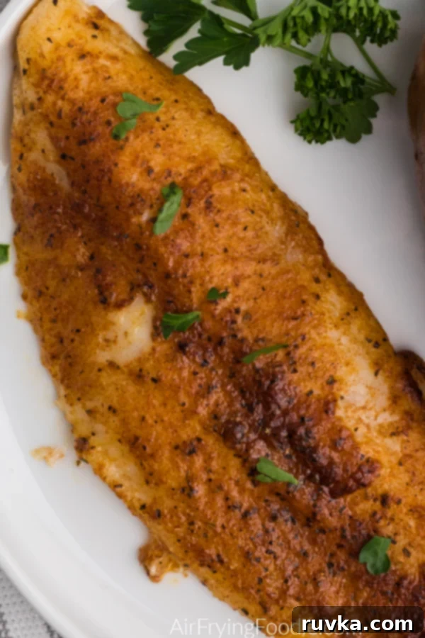 Air Fryer Swai Fish 6 Close up shot of blackened swai fish ion a white plate and topped with fresh parsley.