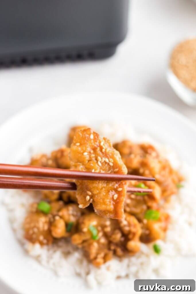 Trader Joes Orange Chicken in the Air Fryer 8 Golden orange chicken piece with sesame seeds being held by chopsticks.