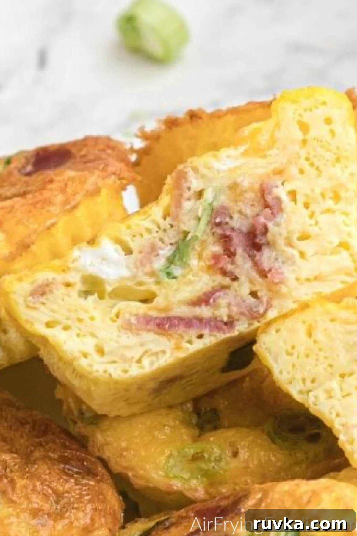 Easy Air Fryer Egg Bites 6 Egg bite sliced in half on a stacked plate with other egg bites.