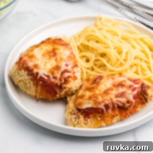Easy Air Fryer Dinners 12 Air Fryer chicken parmesan on a white plate with spaghetti noodles.