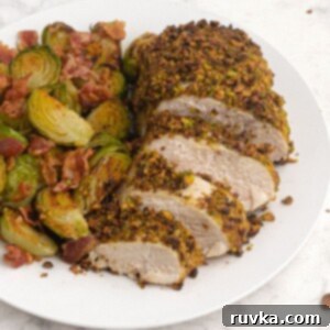 Easy Air Fryer Dinners 16 Cooked and sliced pistachio crusted chicken served with brussel sprouts on a white plate