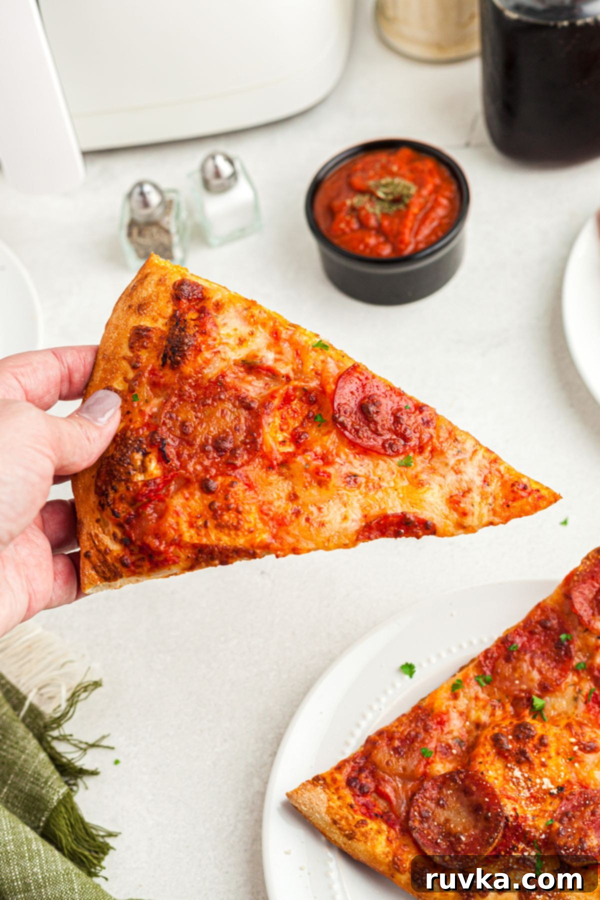 Mastering Air Fryer Leftovers for Crispy Results 3 leftover pizza, slice of pizza being held in hand.