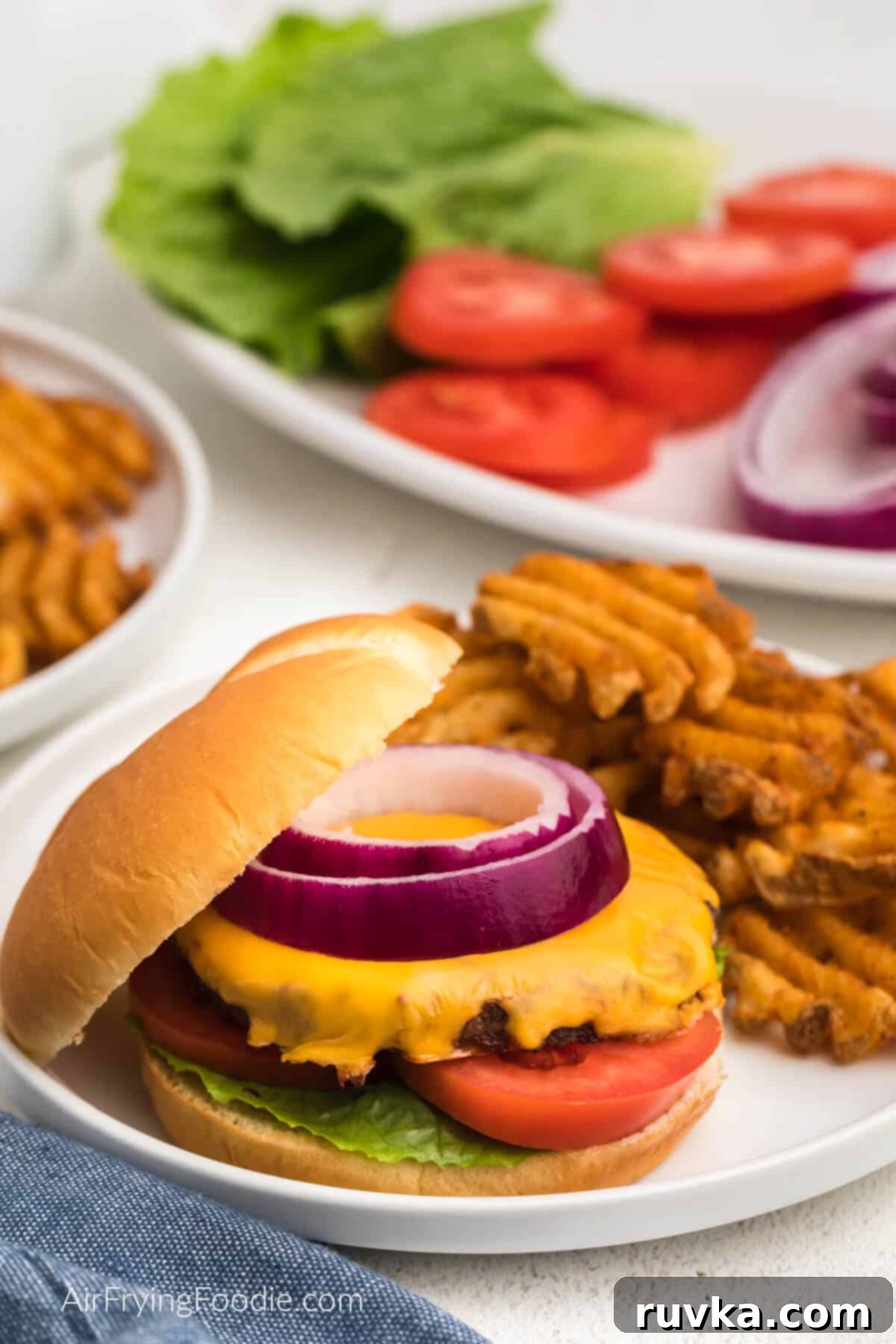 Mastering Air Fryer Leftovers for Crispy Results 9 burger reheated in air fryer topped with cheese and toppings and served with fries on a plate.