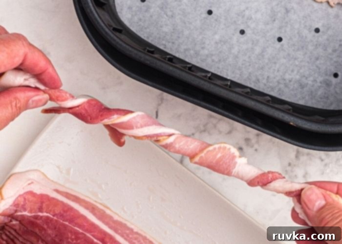 Air Fryer Twisted Bacon 4 Raw bacon being twisted lengthwise, and then place into the air fryer basket, lined with parchment paper with holes.