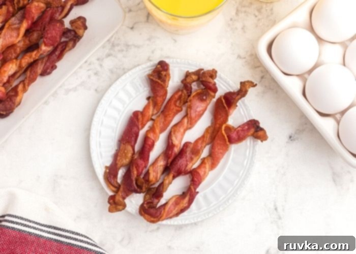 Air Fryer Twisted Bacon 6 Five strips of crispy twisted bacon on a white plate with a tray of eggs next to it.