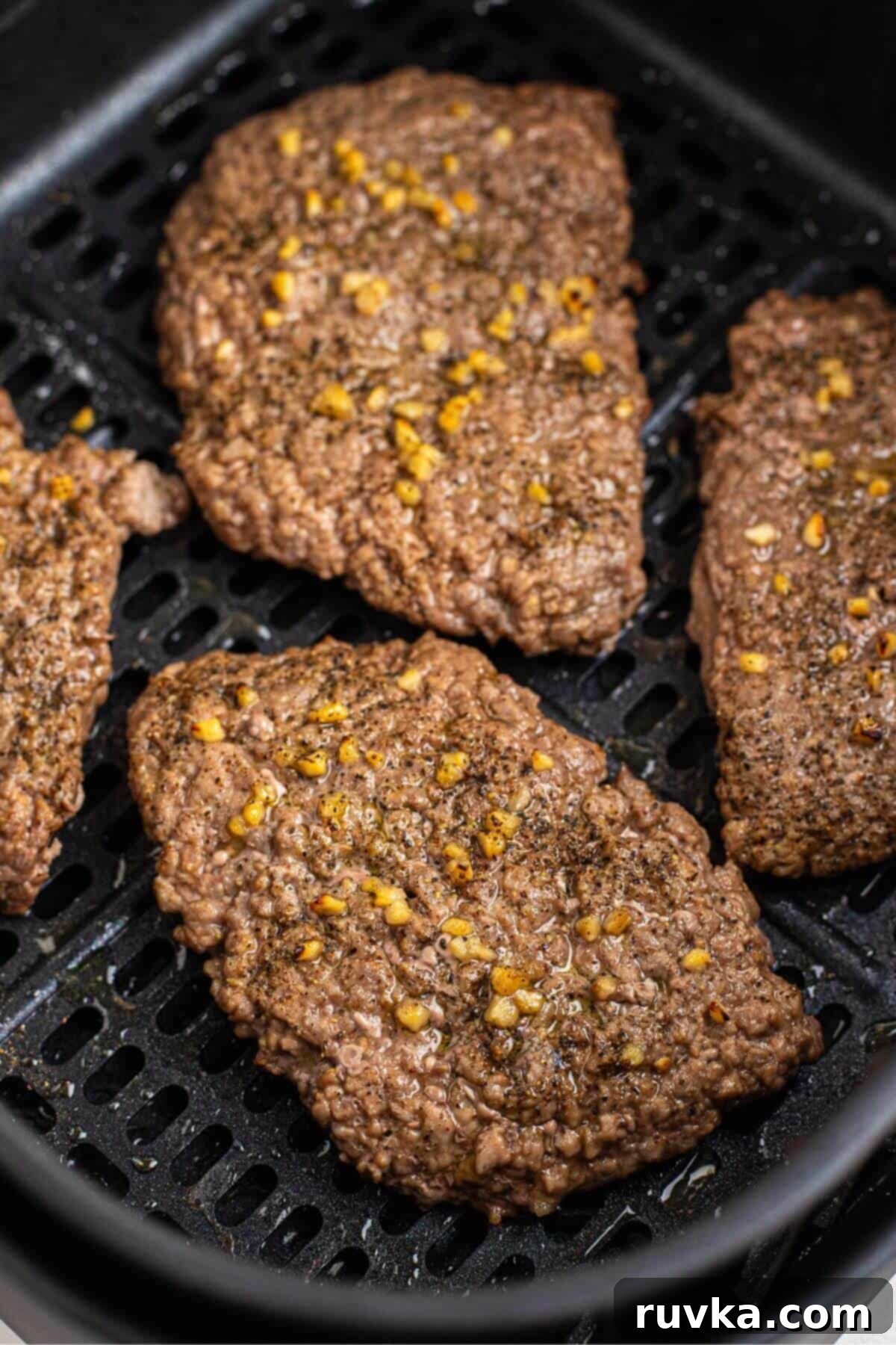 Easy Air Fryer Cube Steak 5 Juicy seasoned cube steak in the air fryer basket after being cooked.