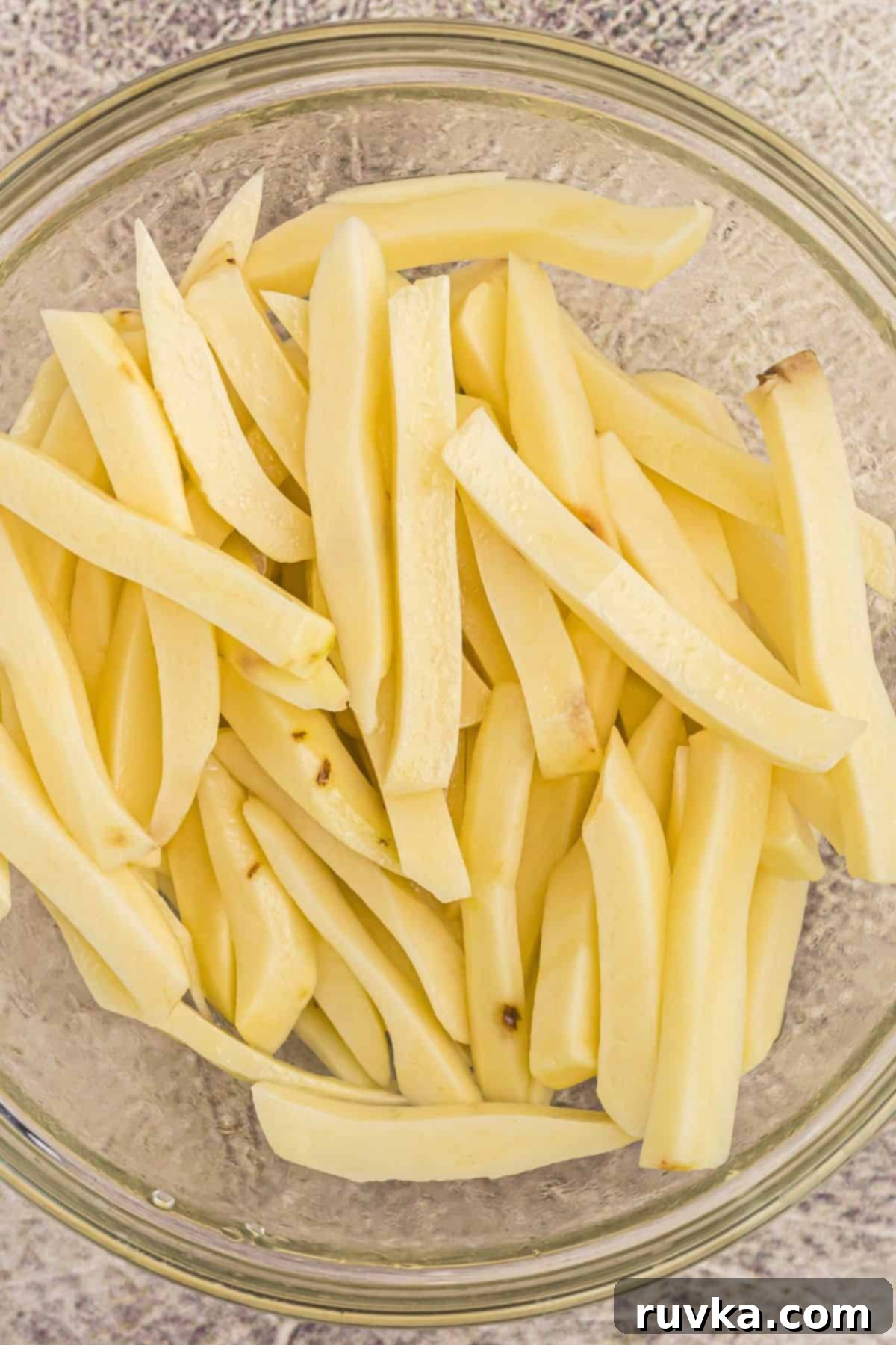 Crispy Air Fryer French Fries 4 Potato slices cut and rinsed in a clear glass bowl.